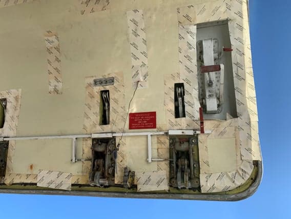 Close-up of the inside of an aircraft door with warning labels and mechanical components.