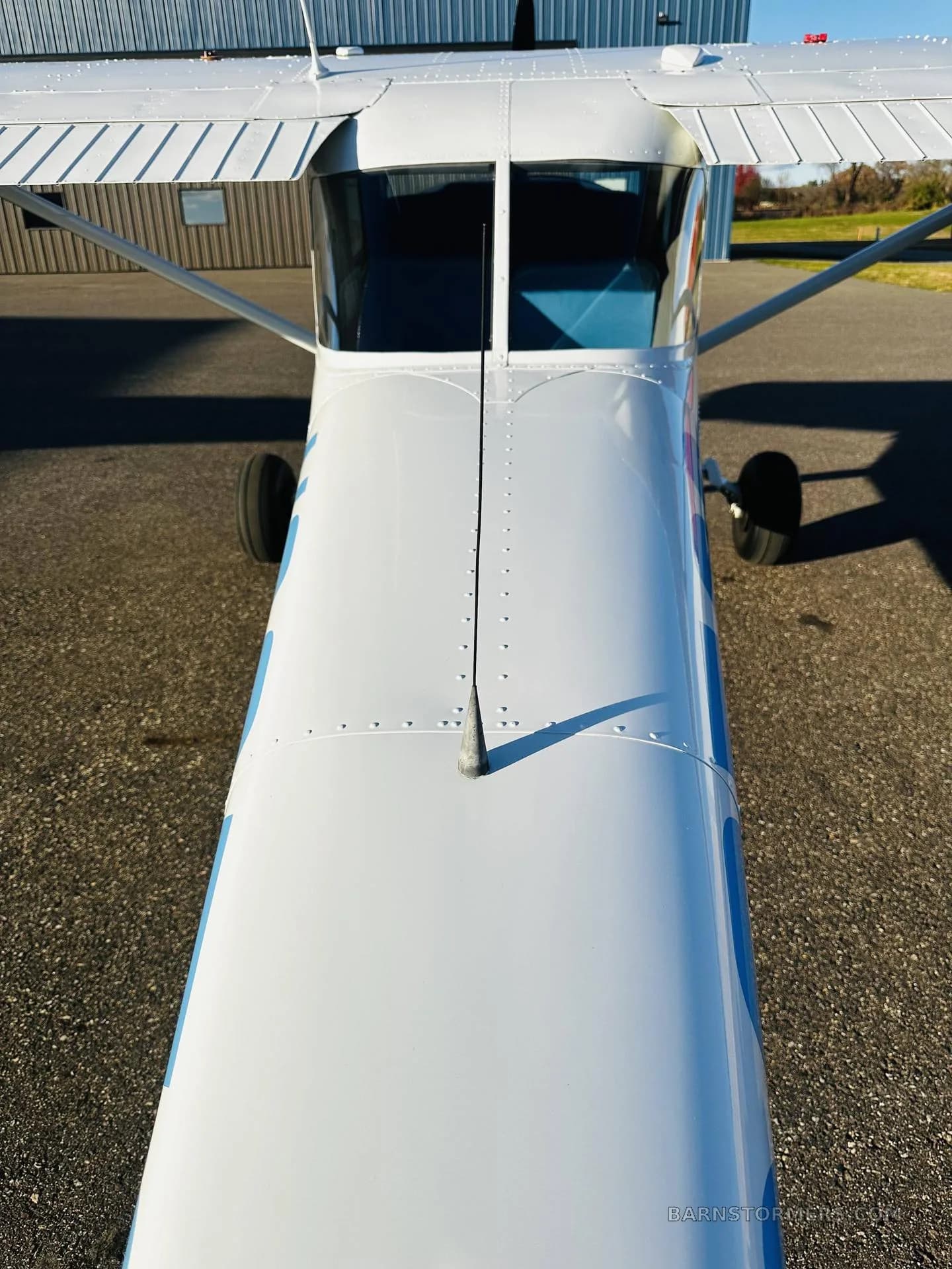 An overhead view looking down the fuselage of a white Cessna 150/152 type aircraft, showing the top of the wings and cockpit.
