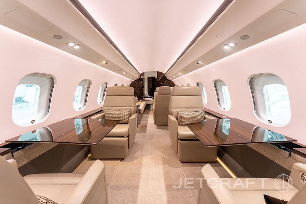 View of the interior of a jet with leather seats and tables.