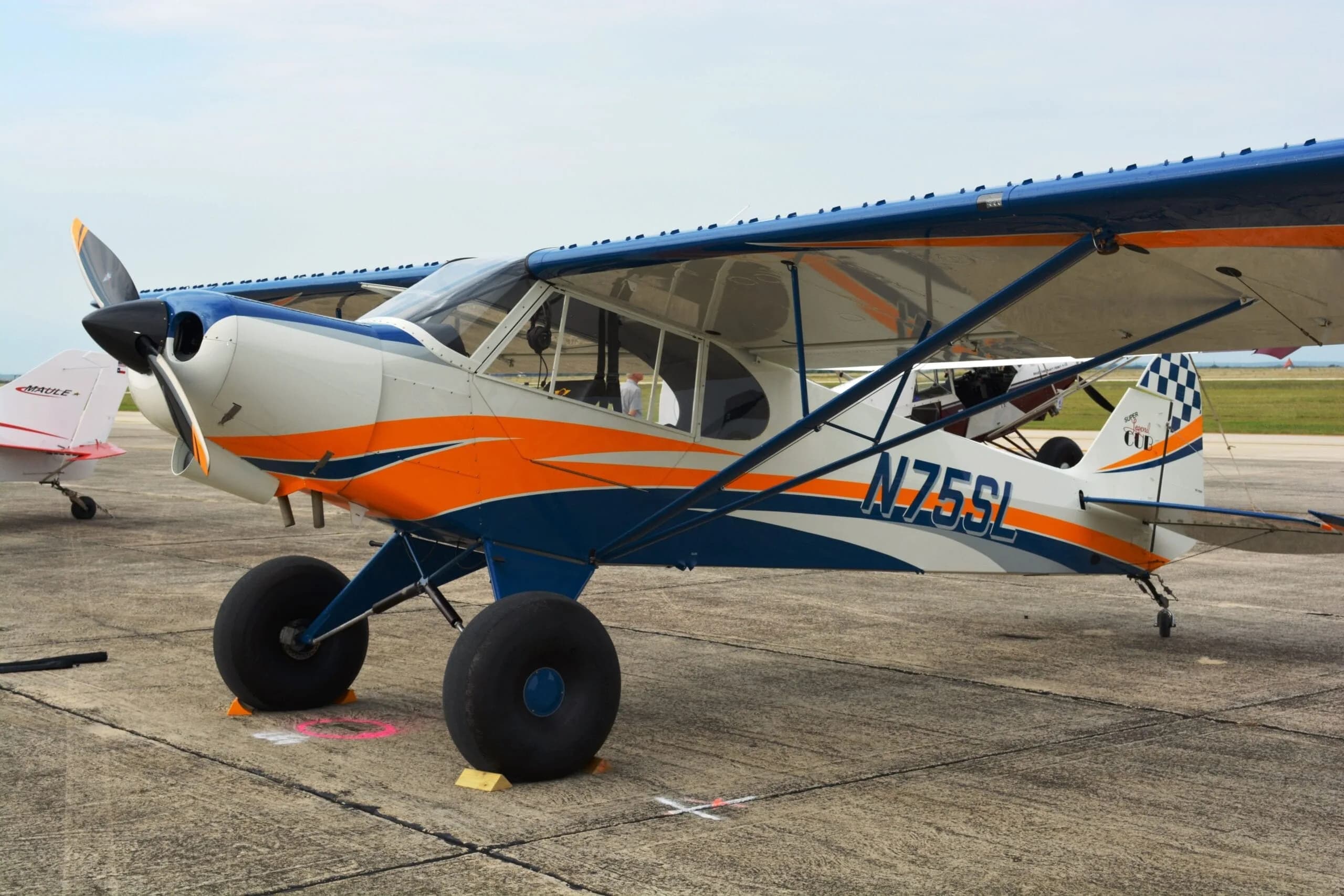 Side view of a white, blue, and orange aircraft with large tires on the ground.