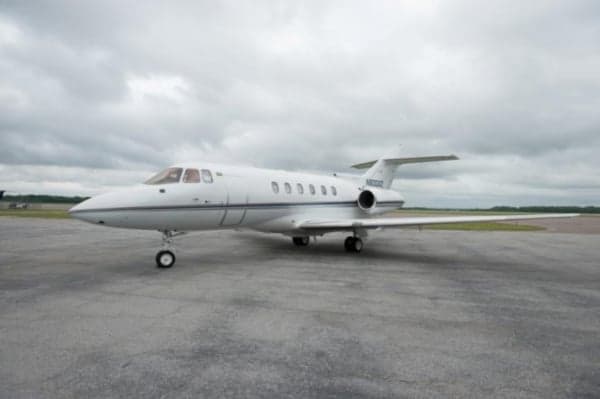 A white jet with blue stripes sits on the tarmac.
