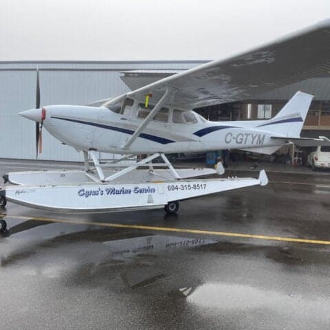C-GTYM Cessna on floats, parked outside a hangar.