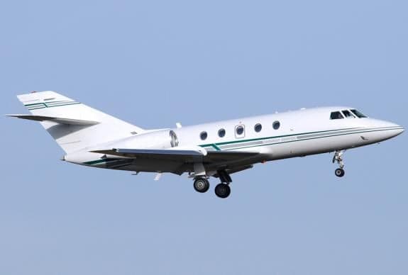 A white and green Falcon jet on approach.
