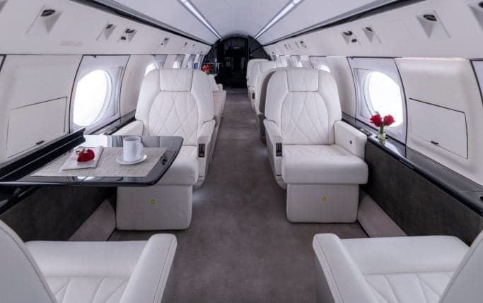 Interior view of the aircraft cabin with white leather seats and a table.