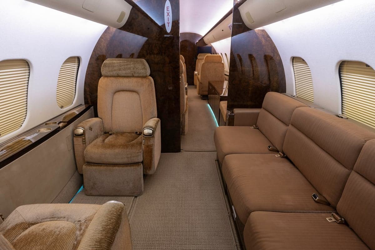 The interior of a Bombardier Global Express aircraft with tan leather seats and wood trim.