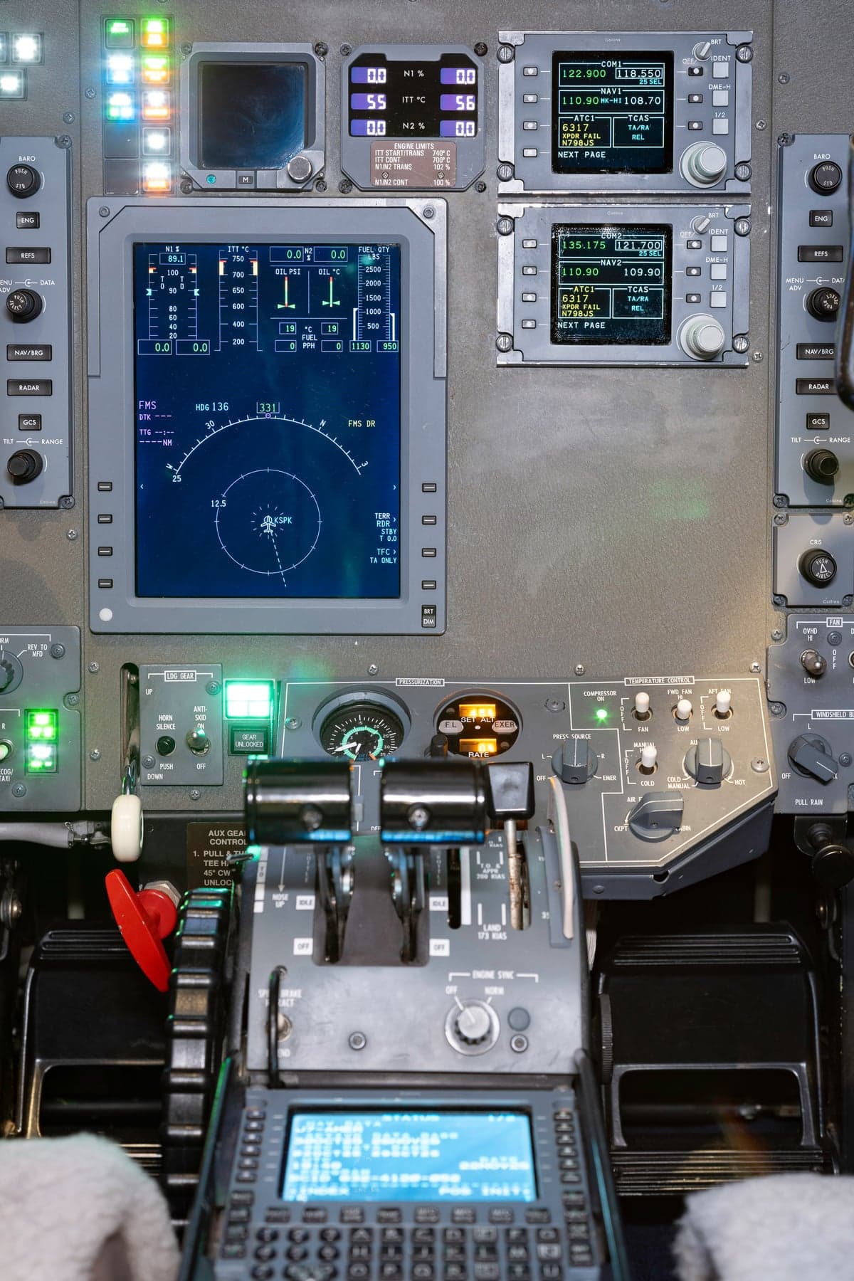 A detailed view of an aircraft's cockpit instrument panel, showing multiple digital displays and the throttle quadrant.