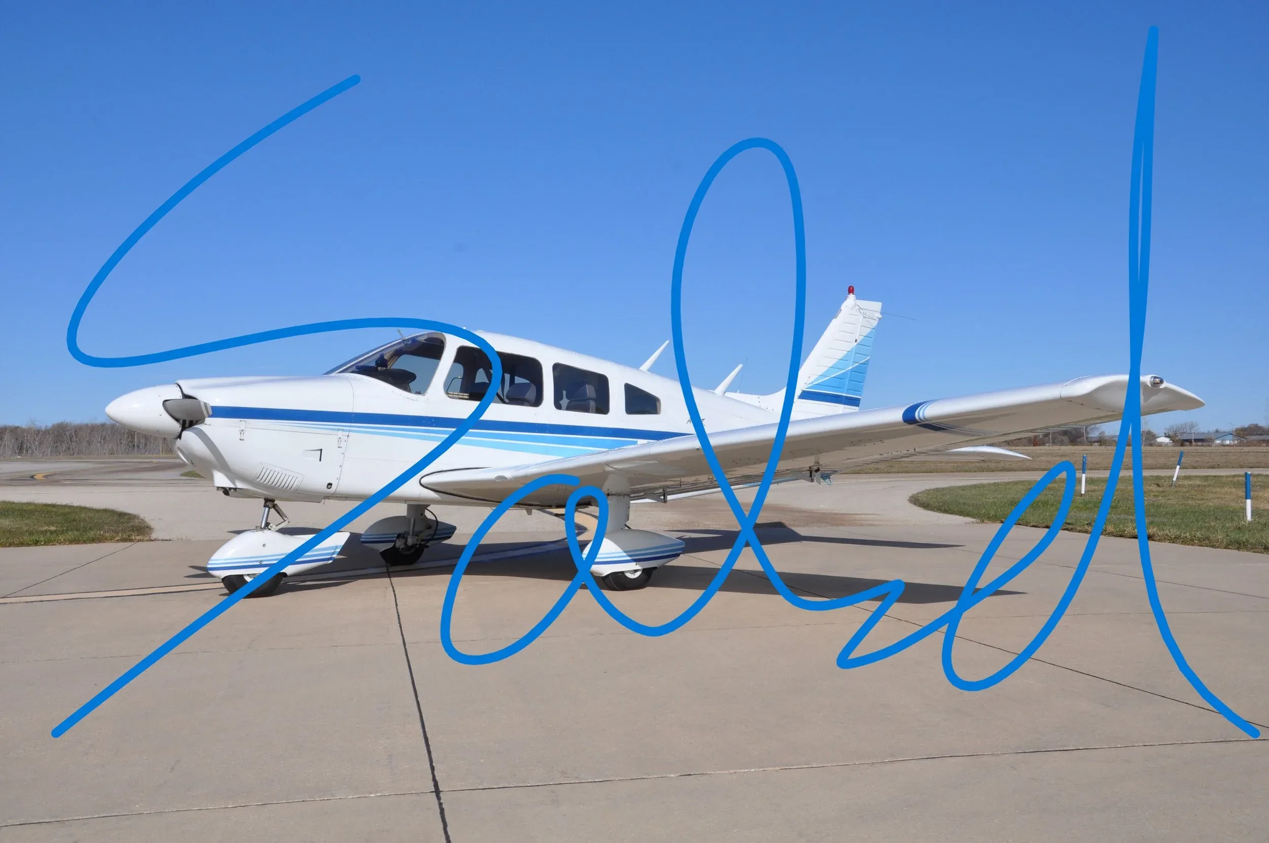 A white single-engine propeller aircraft with blue stripes parked on an asphalt surface under a clear blue sky.