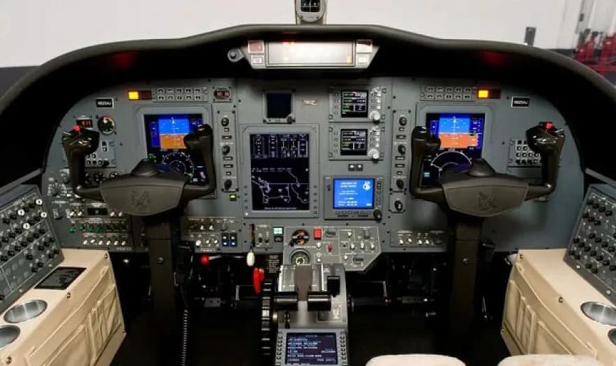 The cockpit of an aircraft featuring multiple digital displays, control yokes, and a central throttle quadrant.