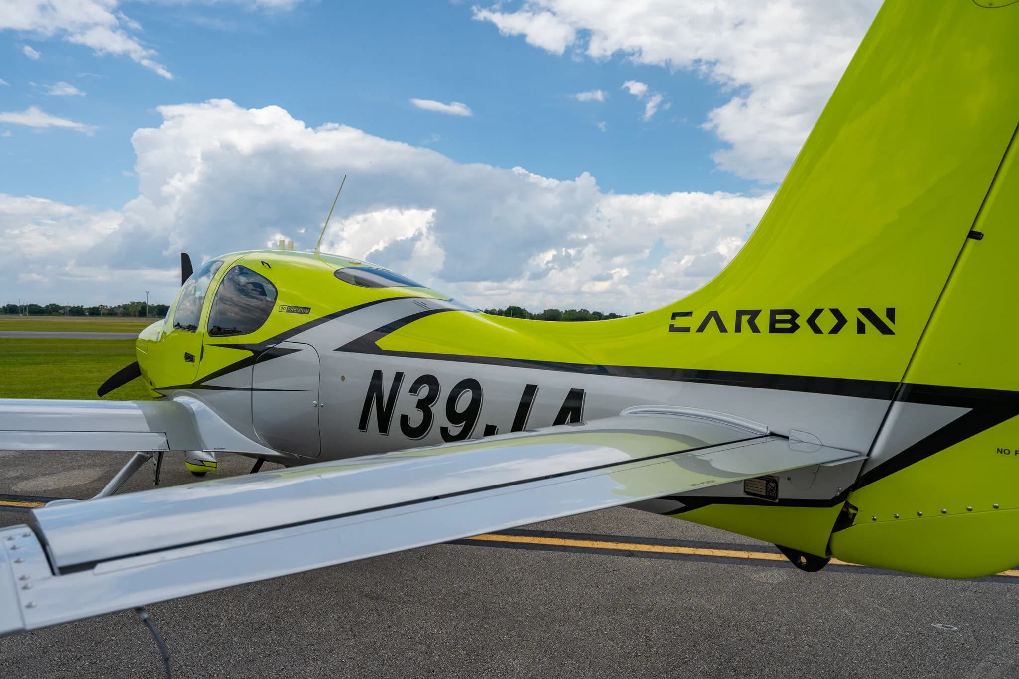 Side view of a lime green and silver Cirrus SR20 aircraft with registration N39JA, parked on an asphalt ramp.