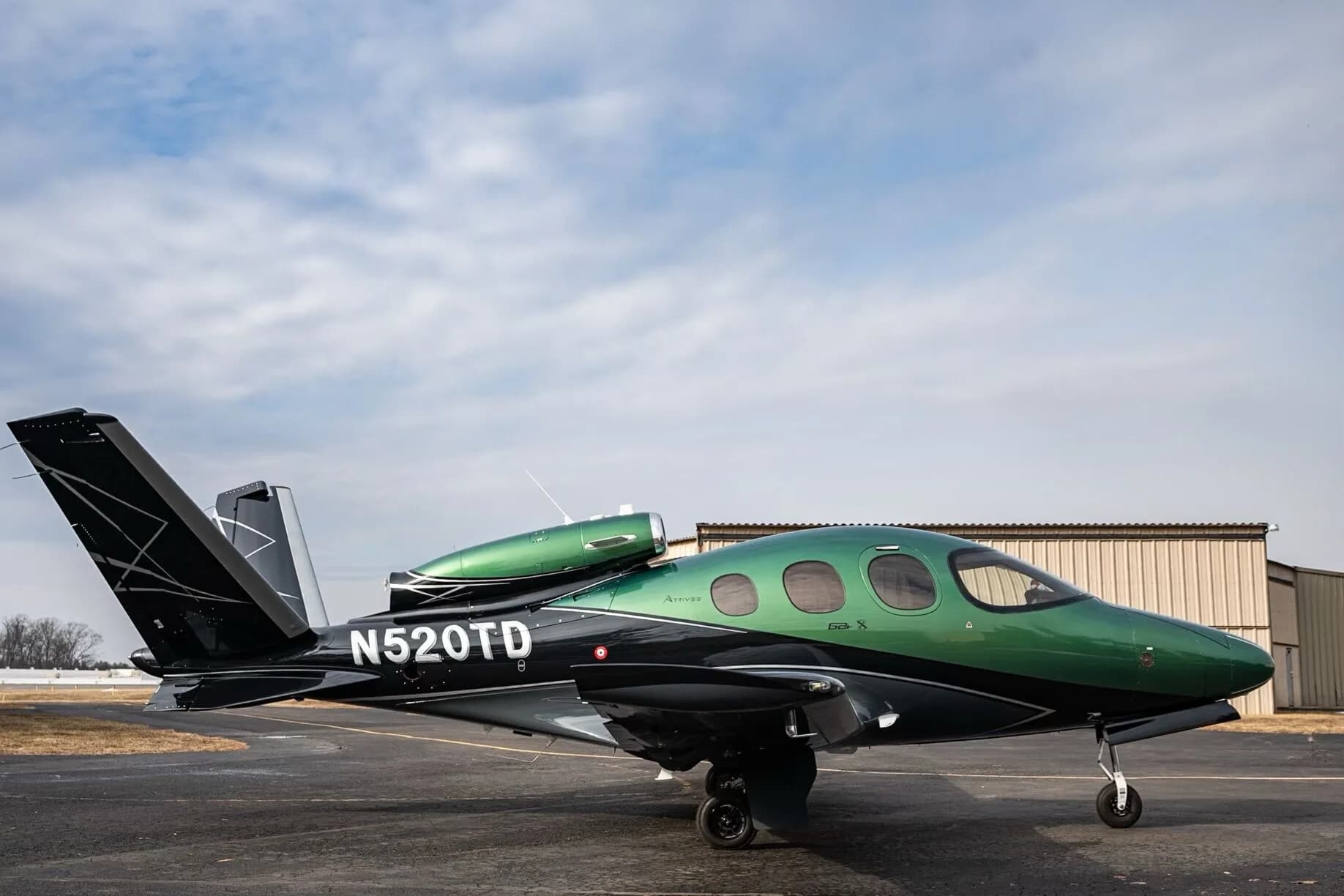 A Cirrus Vision Jet N520TD in a striking green and black paint scheme parked on an airfield.