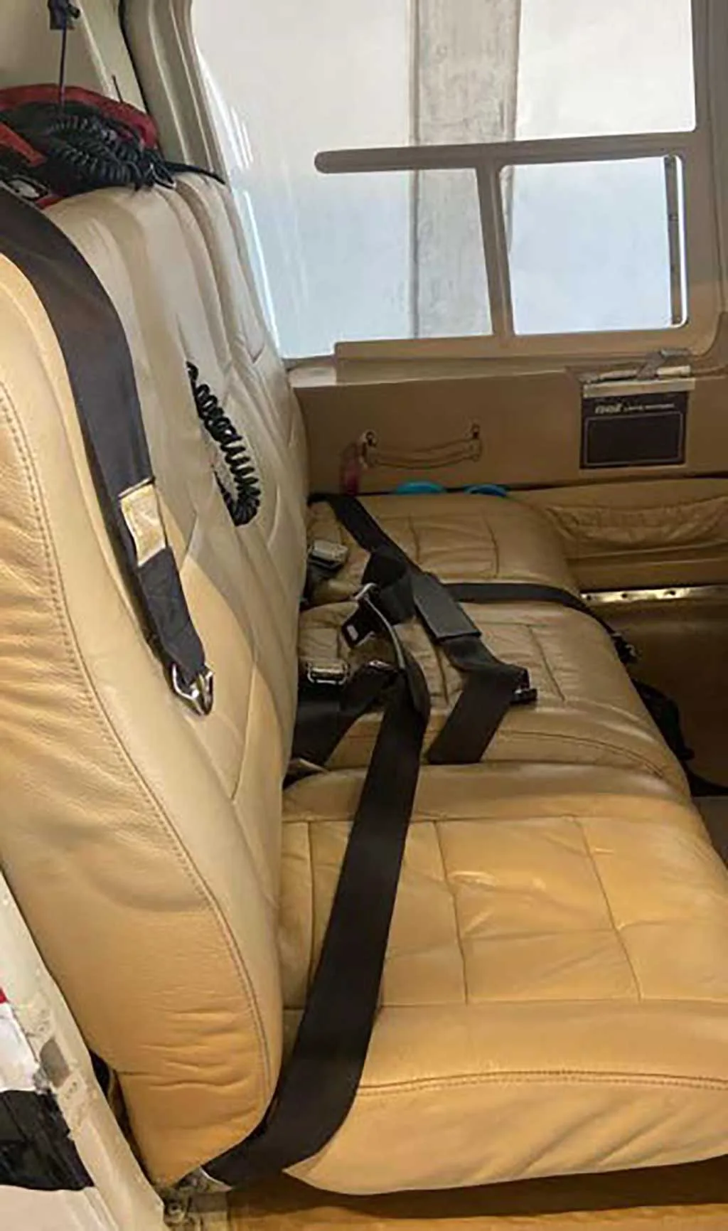 A view of the tan leather bench seat in the rear cabin of a helicopter.