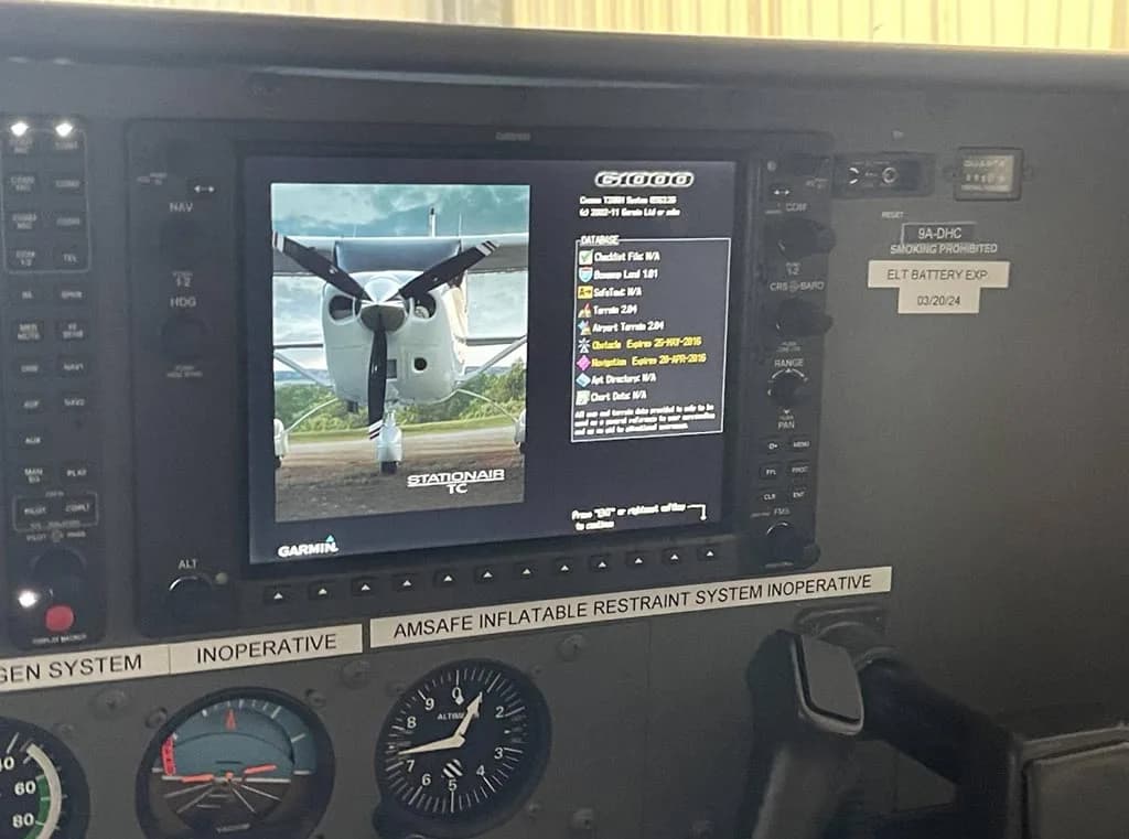 A close-up of the Garmin G1000 display in the cockpit, showing a menu and an image of a propeller aircraft.