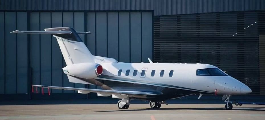 A light jet aircraft parked in front of a hangar.