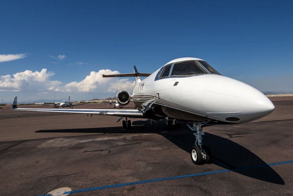 A front-quarter view of the white and black business jet N751MT with gold stripes, parked on an airport tarmac.