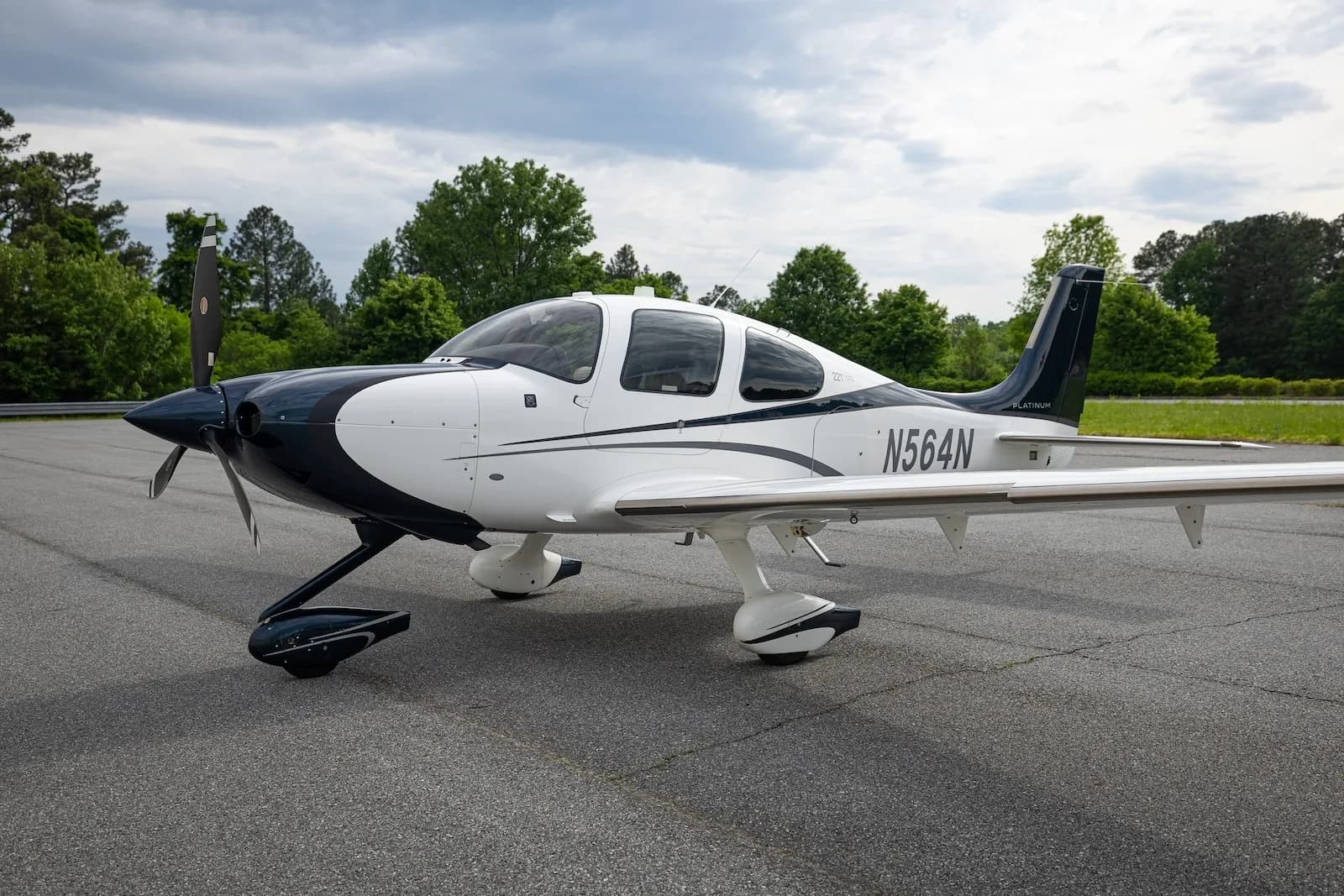 A white and dark blue Cirrus SR22T aircraft with registration N564N parked on an asphalt ramp.