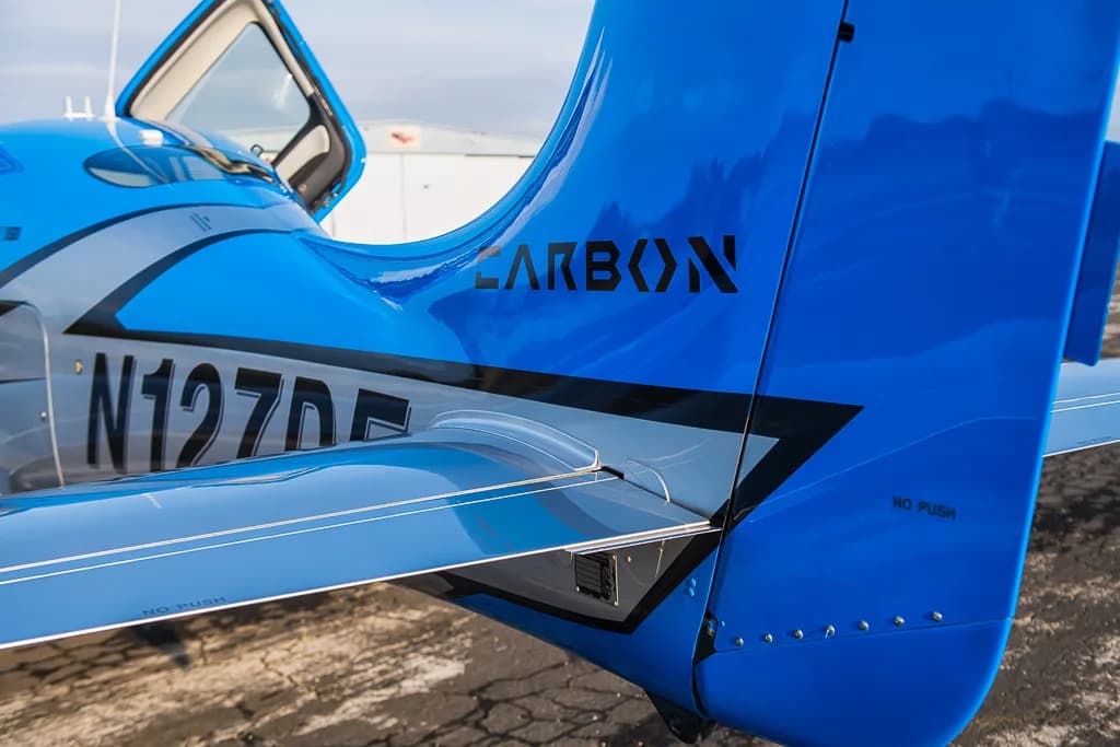 A close-up view of the blue tail and silver fuselage of the Cirrus SR22T GTS Carbon aircraft (N127DF) with "CARBON" branding.
