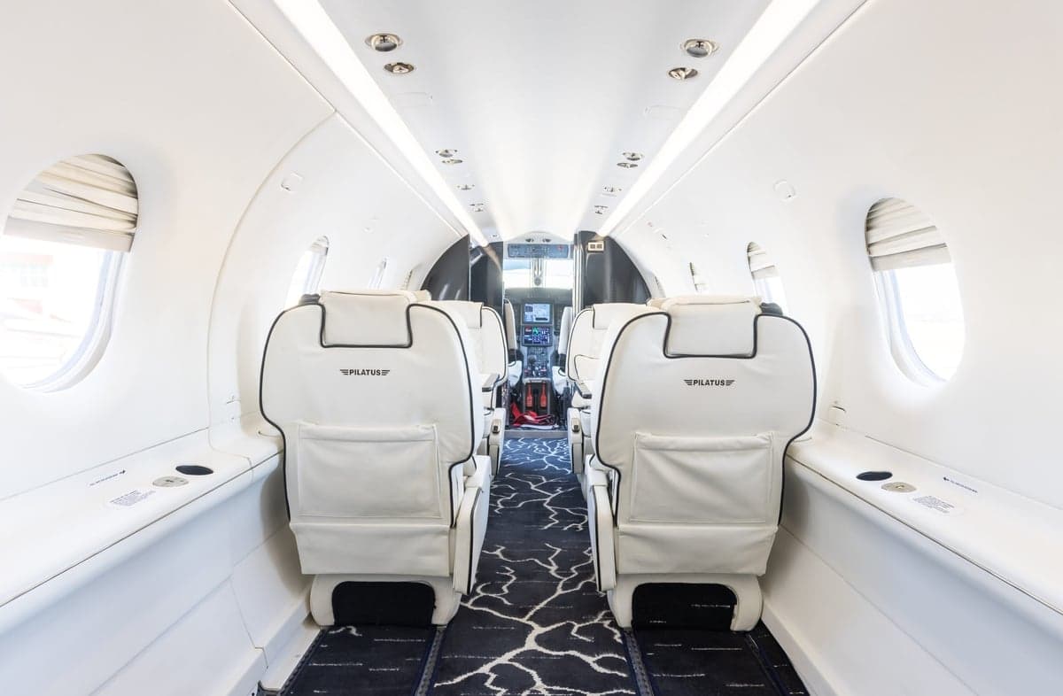 The interior of a Pilatus PC-24 aircraft, showing the rear seats and cabin layout.
