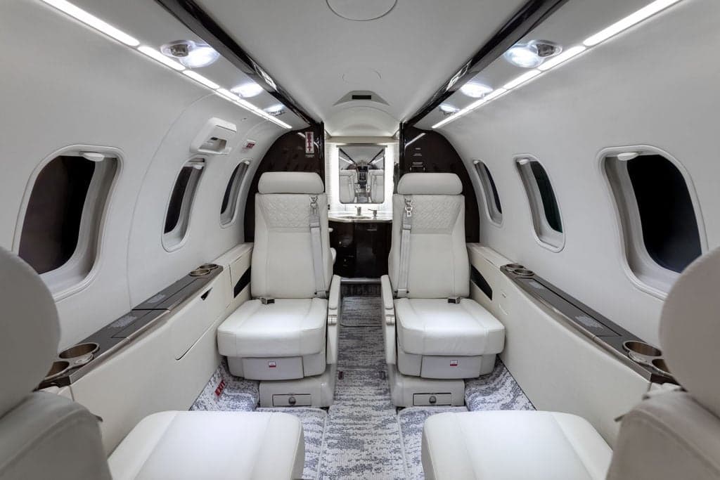 View of the aircraft's interior with white leather seats and carpeted floor.