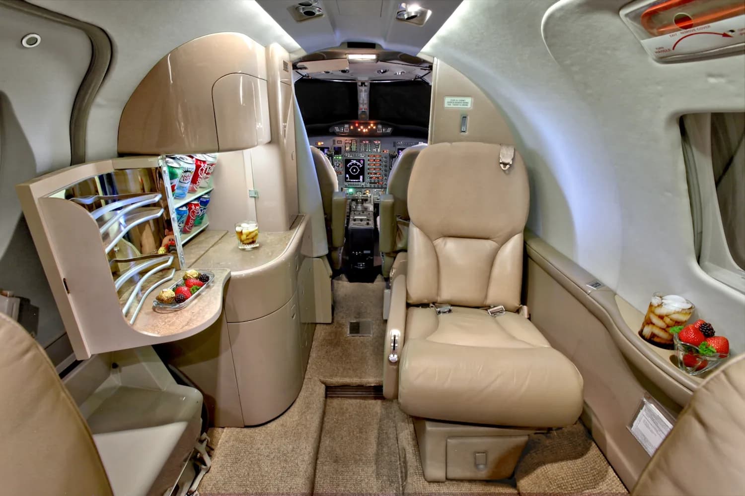 A view of the interior of a jet with tan leather seats and a magazine on the table.