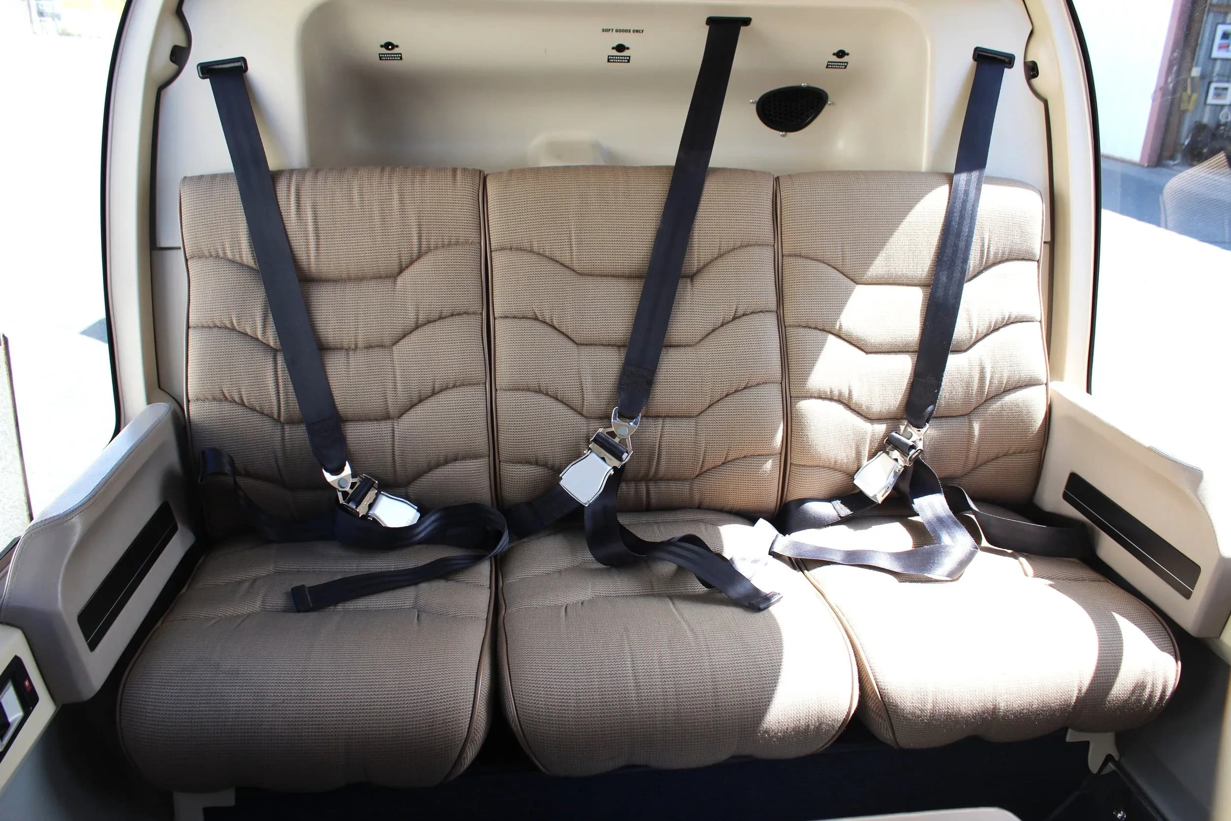 The interior of a helicopter with three seats and seatbelts.