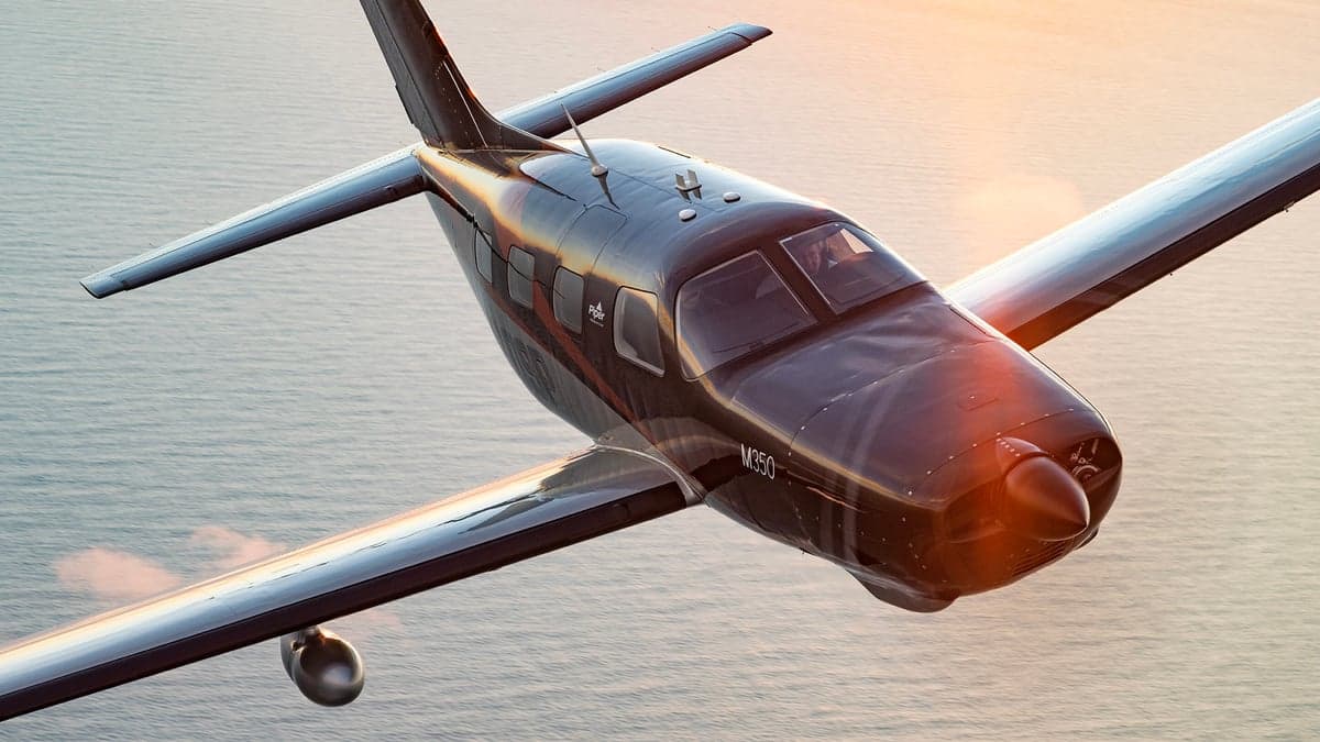 Piper M350 in flight over water.