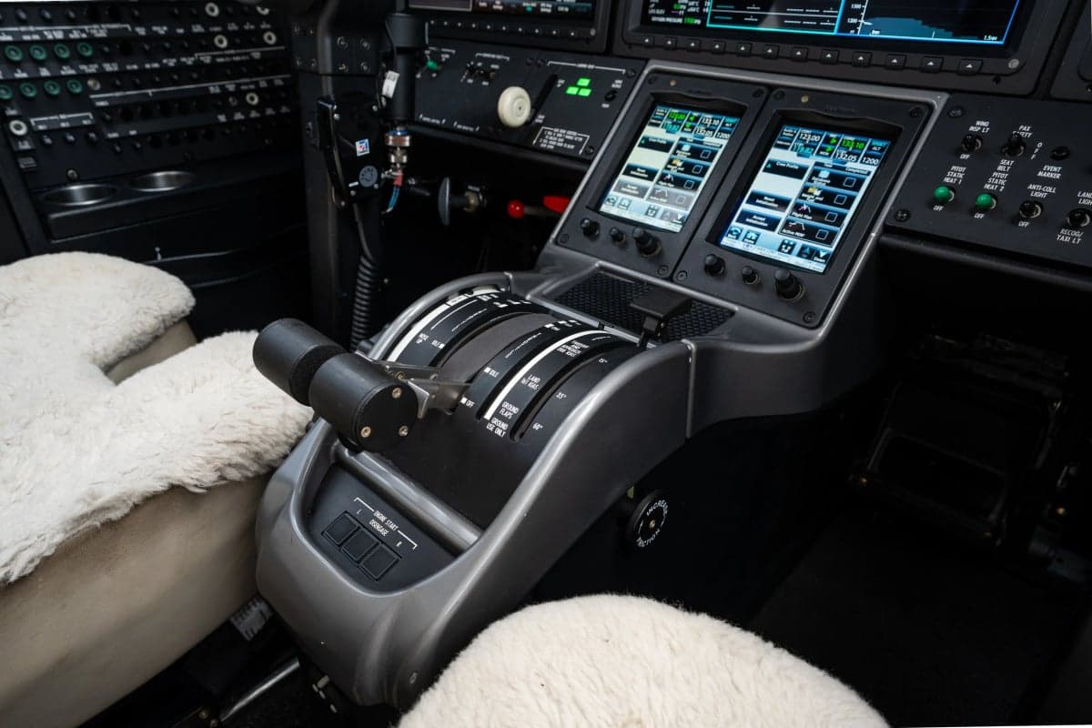 Close-up of the aircraft's throttle controls and instrument panel screens.