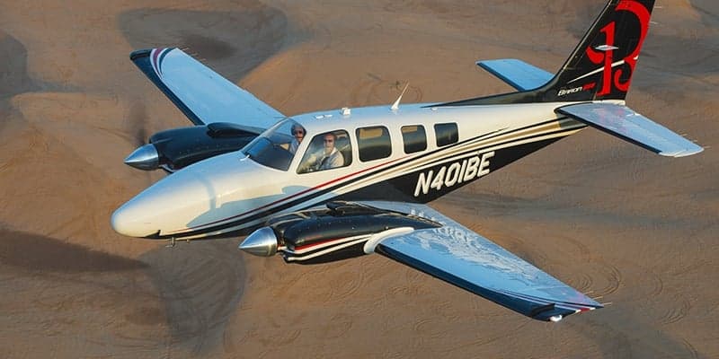 Beechcraft Baron flying over a desert landscape.