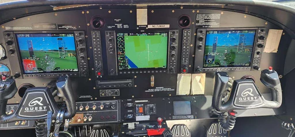The aircraft's cockpit with a modern glass panel display, featuring multiple screens and "QUEST AIRCRAFT COMPANY" on the yokes.