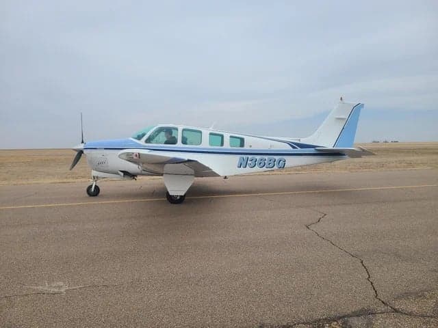 A white and blue Beechcraft Bonanza with registration N36BG sits on the tarmac.