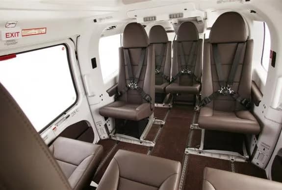 Interior view of the helicopter cabin with brown leather seats and seatbelts.
