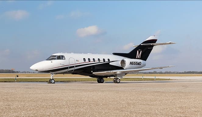 A black and white aircraft with a large 'M' on the tail sits on the tarmac.