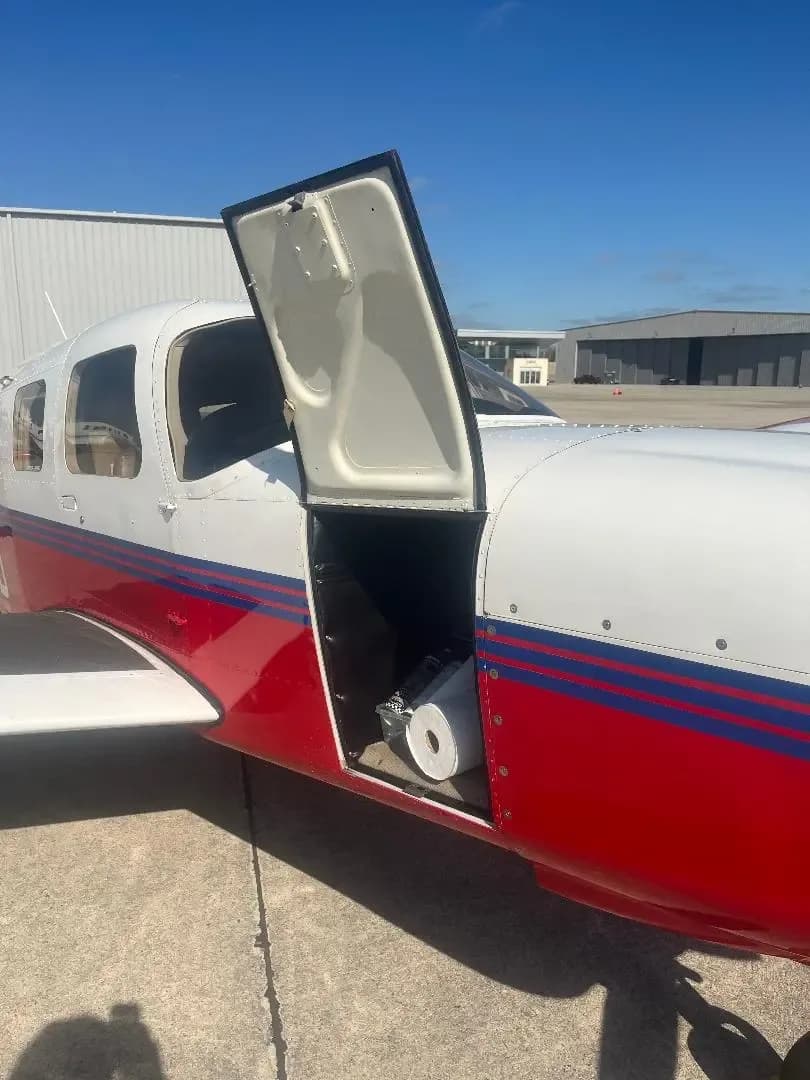 A red and white aircraft, N3258H, with its cargo door open, revealing a large roll of material inside.