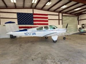 Side view of a Beechcraft Bonanza aircraft with registration N7173N in a hangar.
