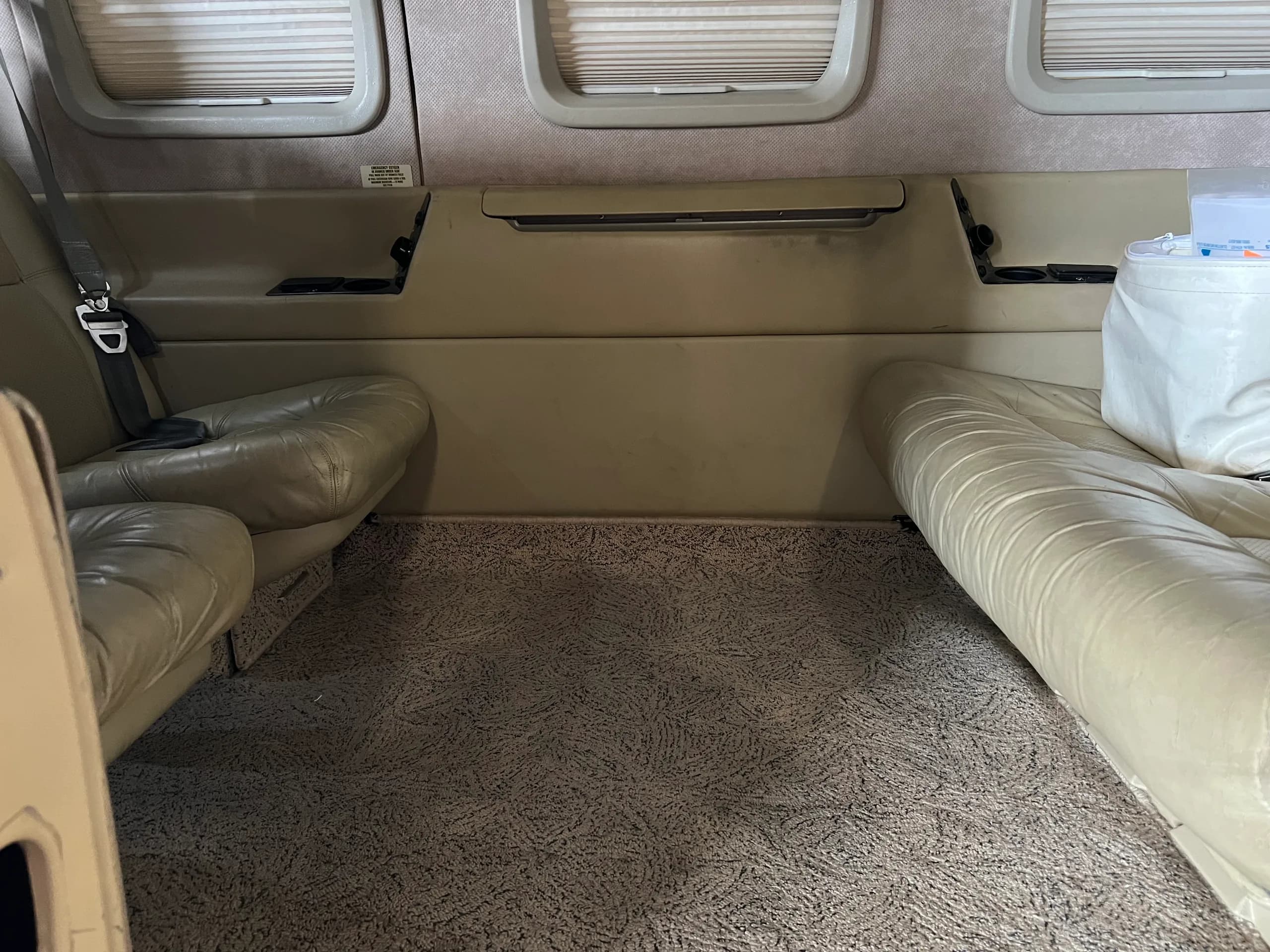 The rear cabin interior of the Piper Mirage aircraft, showing beige leather seats, patterned carpet, and window shades.