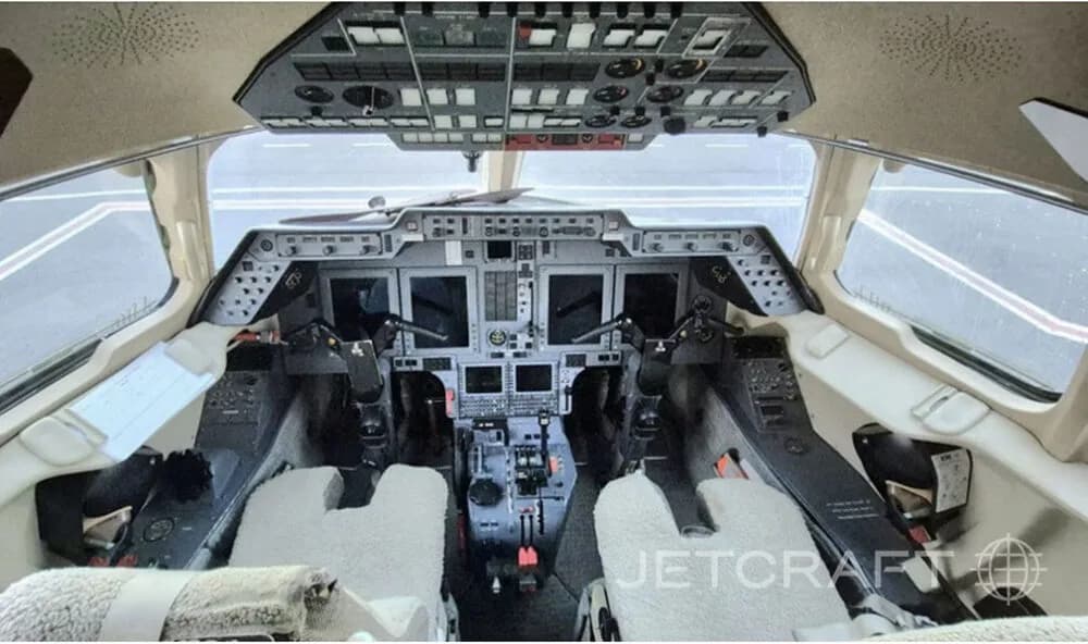 The cockpit of a business jet, showing the instrument panel, multiple displays, and control yokes.
