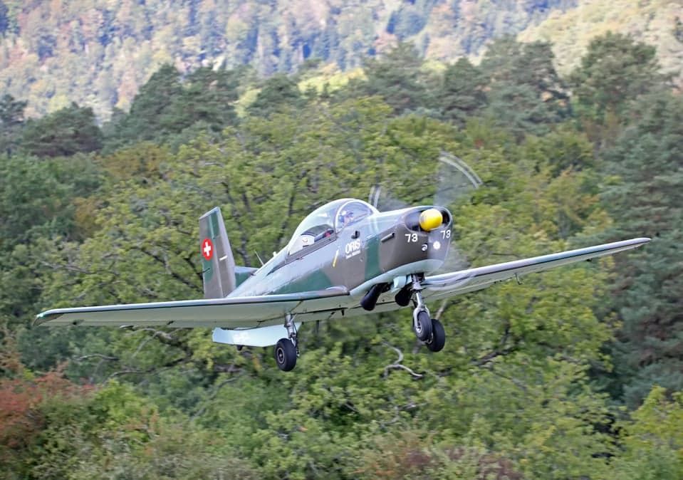 Pilatus PC-7 in flight over a forest.