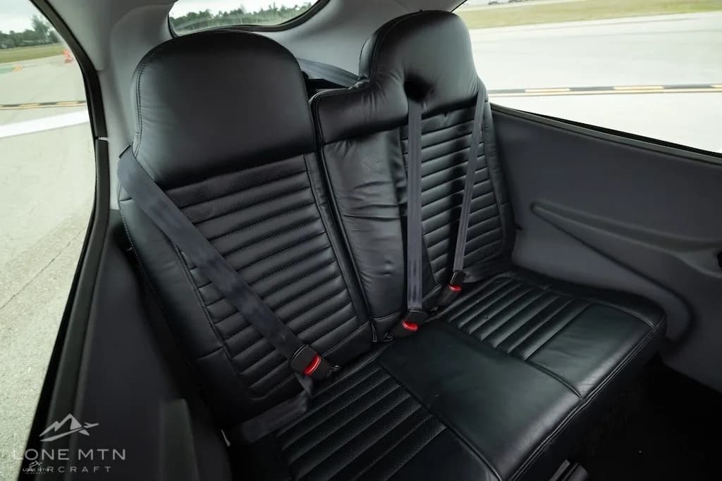 The black leather rear seats of a Cirrus SR20 aircraft cabin, showing seatbelts.