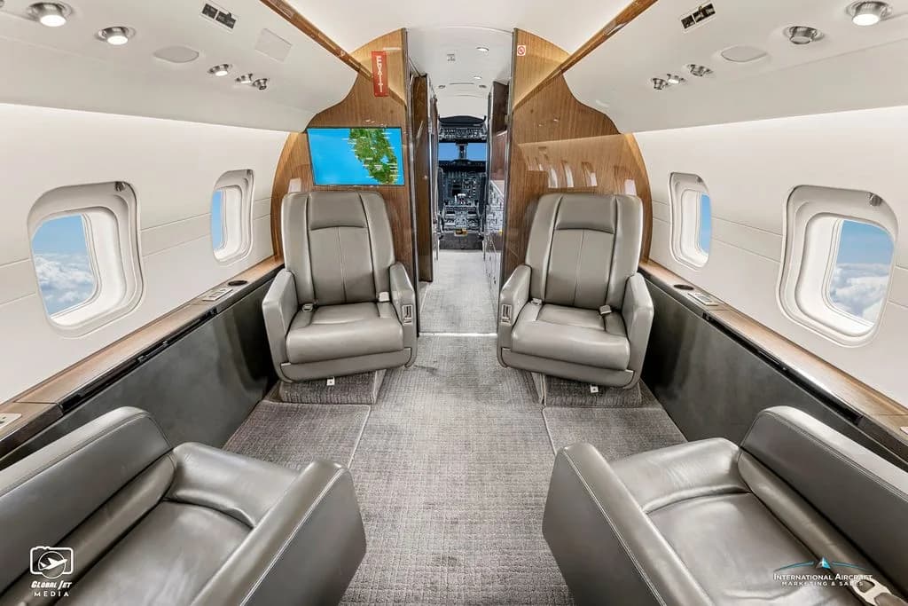 View of the Challenger aircraft cabin with leather seats and wood trim.
