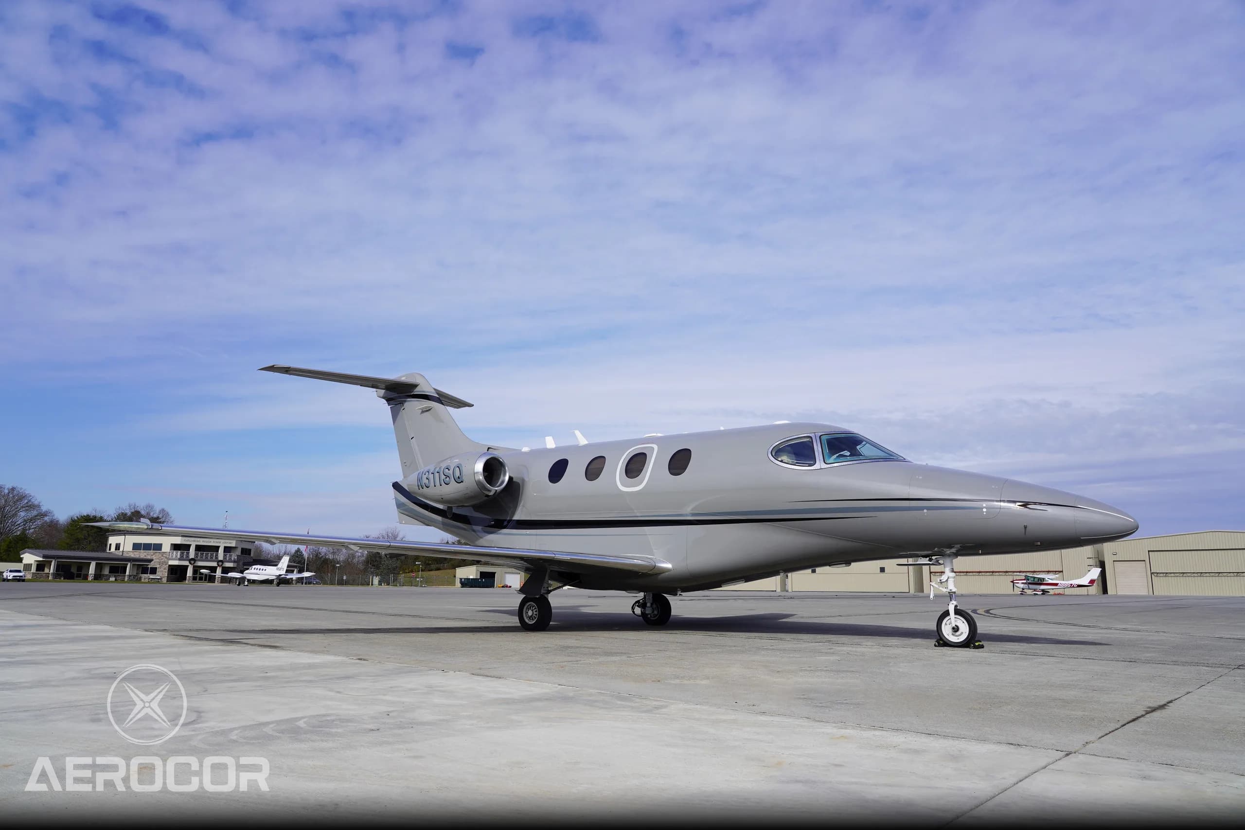 A front-side view of the gray Raytheon Premier I business jet, registration N311SQ, parked on a tarmac.