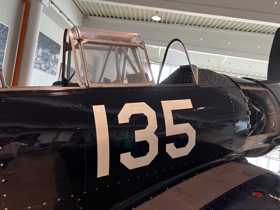 Side view of a navy blue North American T-6 Texan inside a hangar.