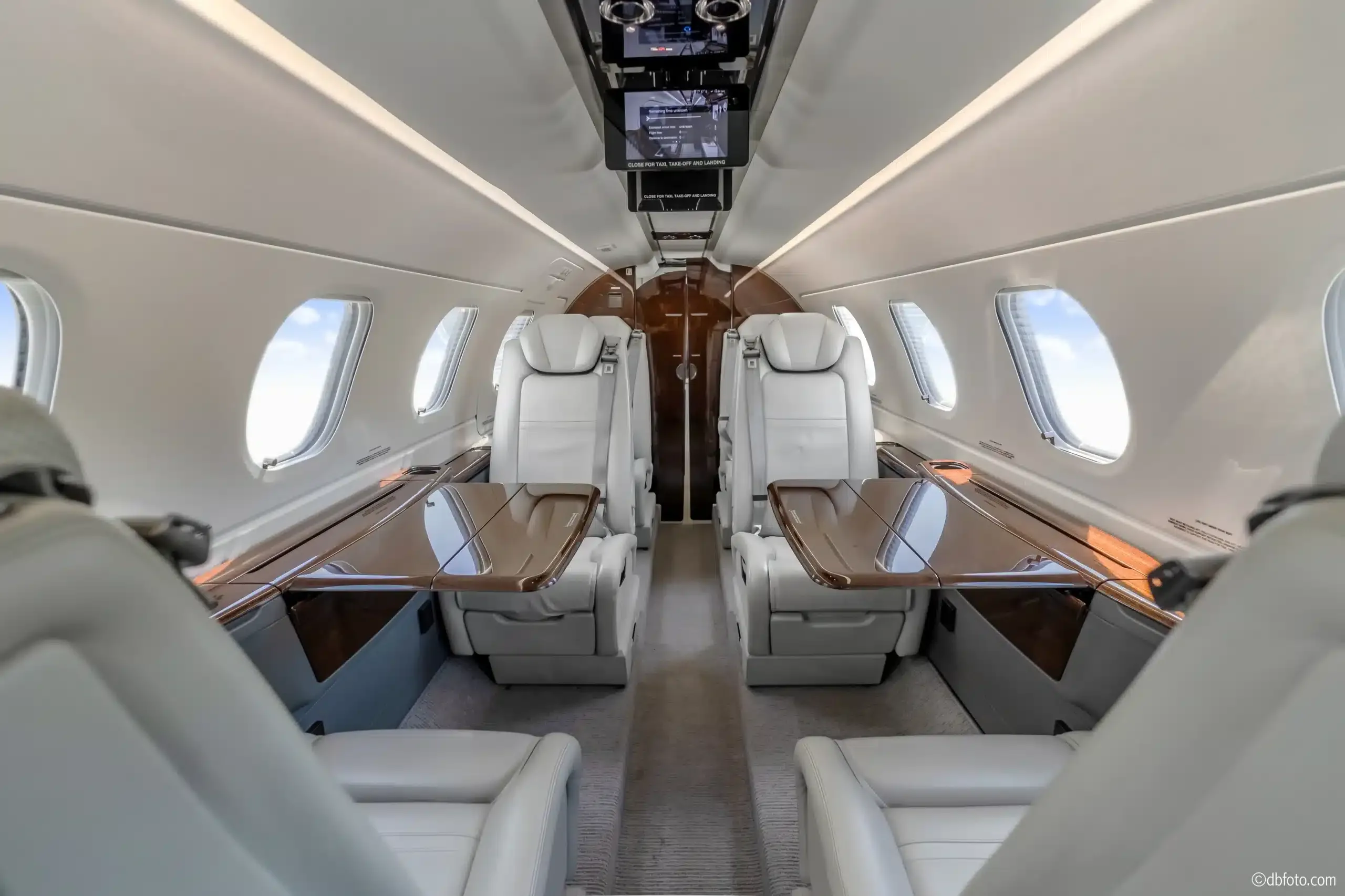 Aircraft cabin with leather seats and tables.