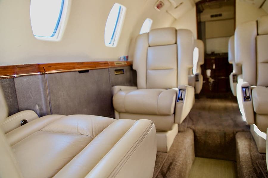 Interior view of an aircraft cabin with cream-colored leather seats.