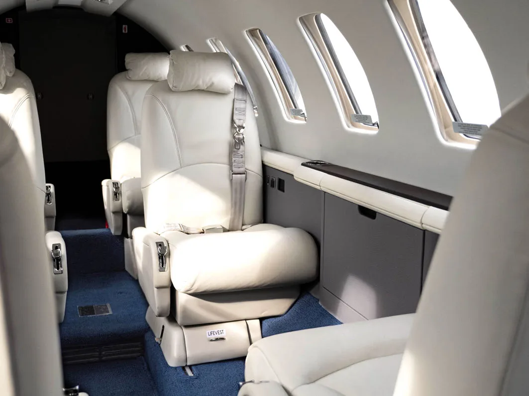 Aircraft interior with white leather seats and side console.