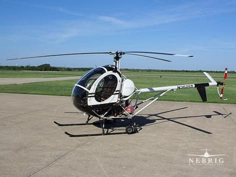 A black and white Rotorway Exec 162F helicopter, tail number N3625T, sits on a concrete pad at an airfield.