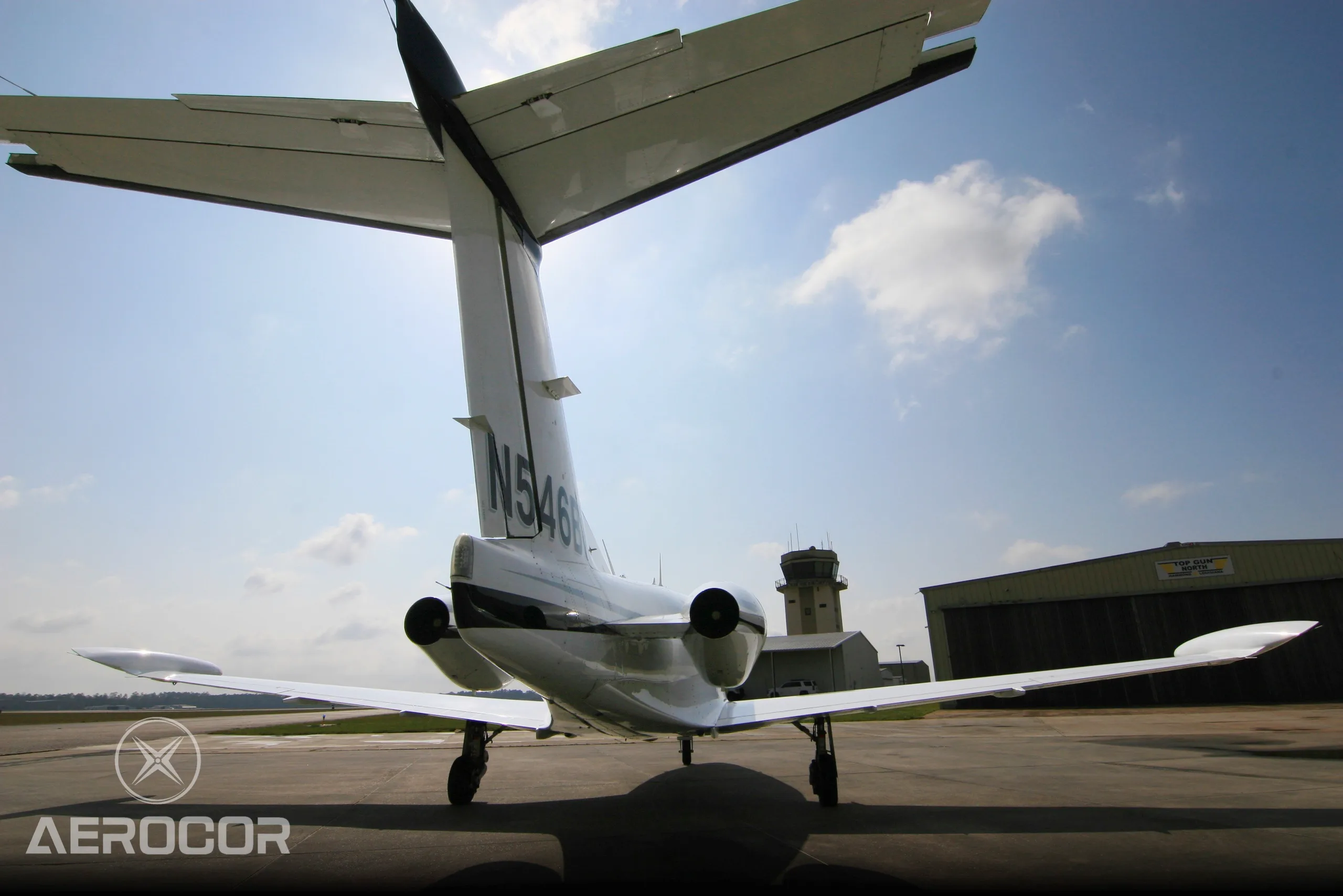 A low-angle rear view of a white Eclipse 500 jet showing its tail and engines on an airfield.