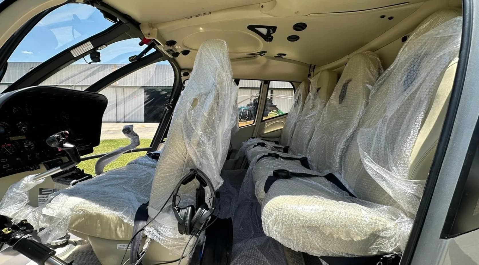 Interior view of the Eurocopter EC130 B4 helicopter cabin with seats covered in plastic.