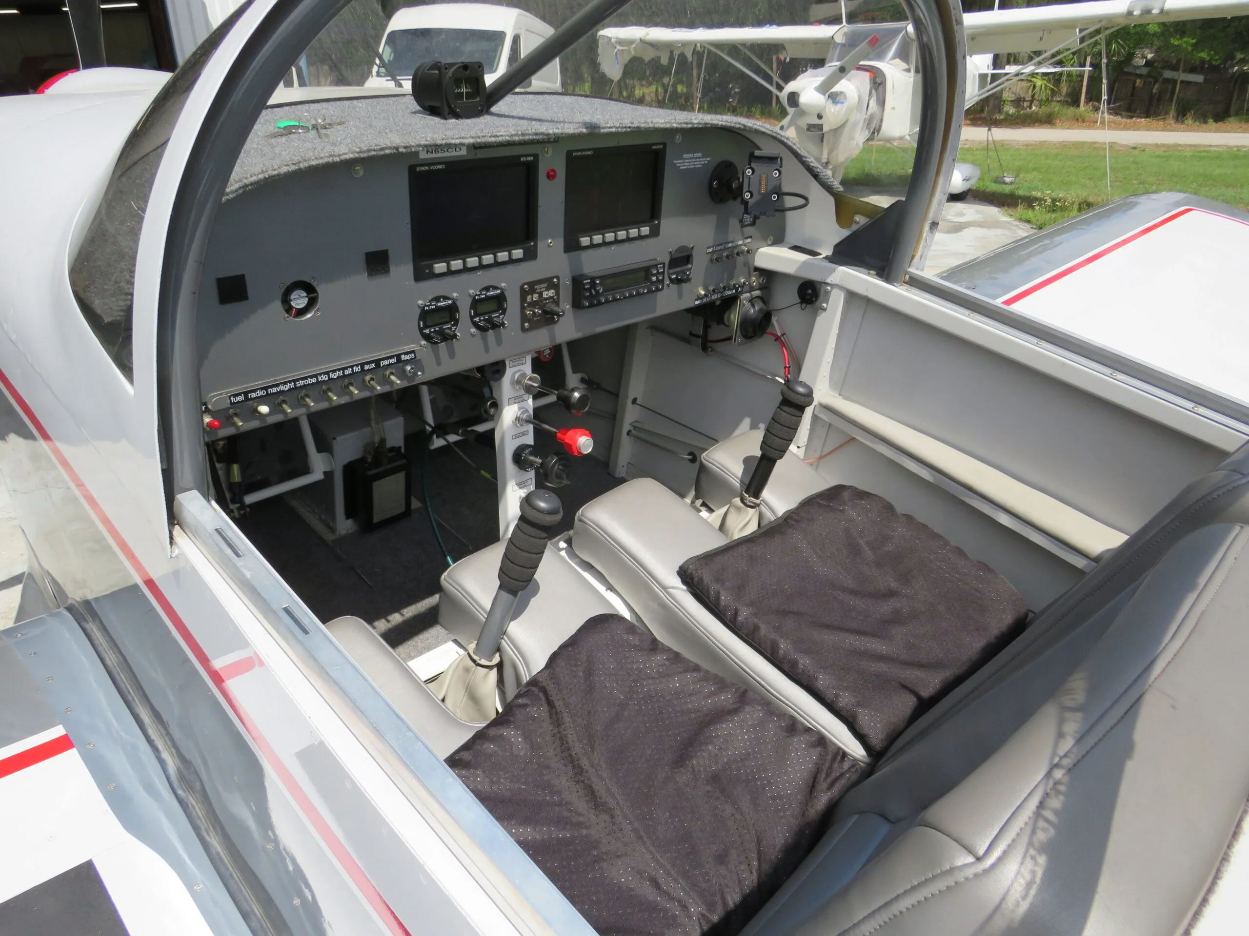 Overhead view of the aircraft's cockpit showing the instrument panel, controls, and two grey seats with black cushions.