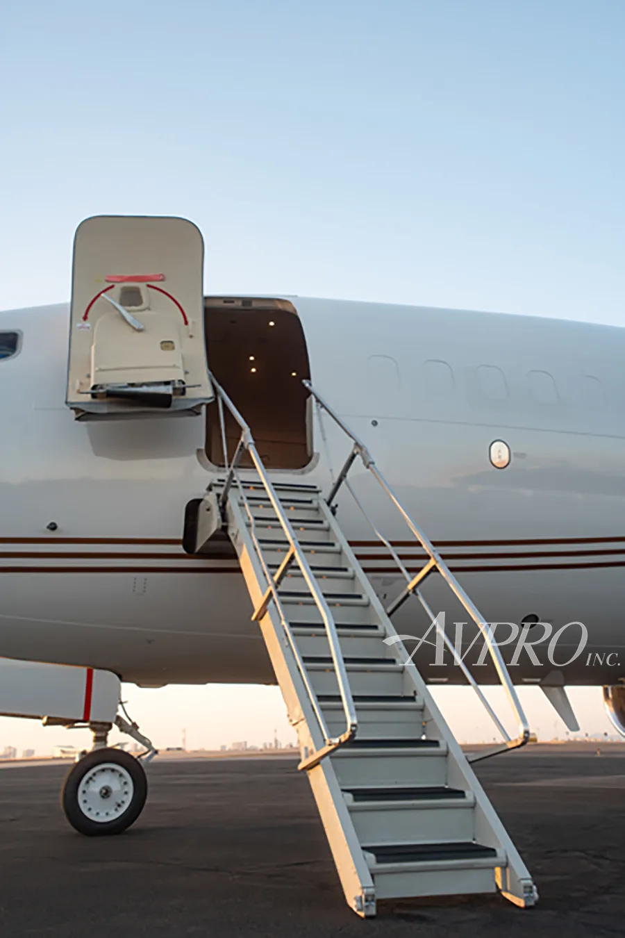 A close-up view of the open main door and extended stairs of a white Boeing 737 business jet.