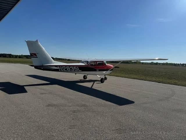 A red and white Cessna 172, registration N2835L, parked on an asphalt runway under a clear blue sky.