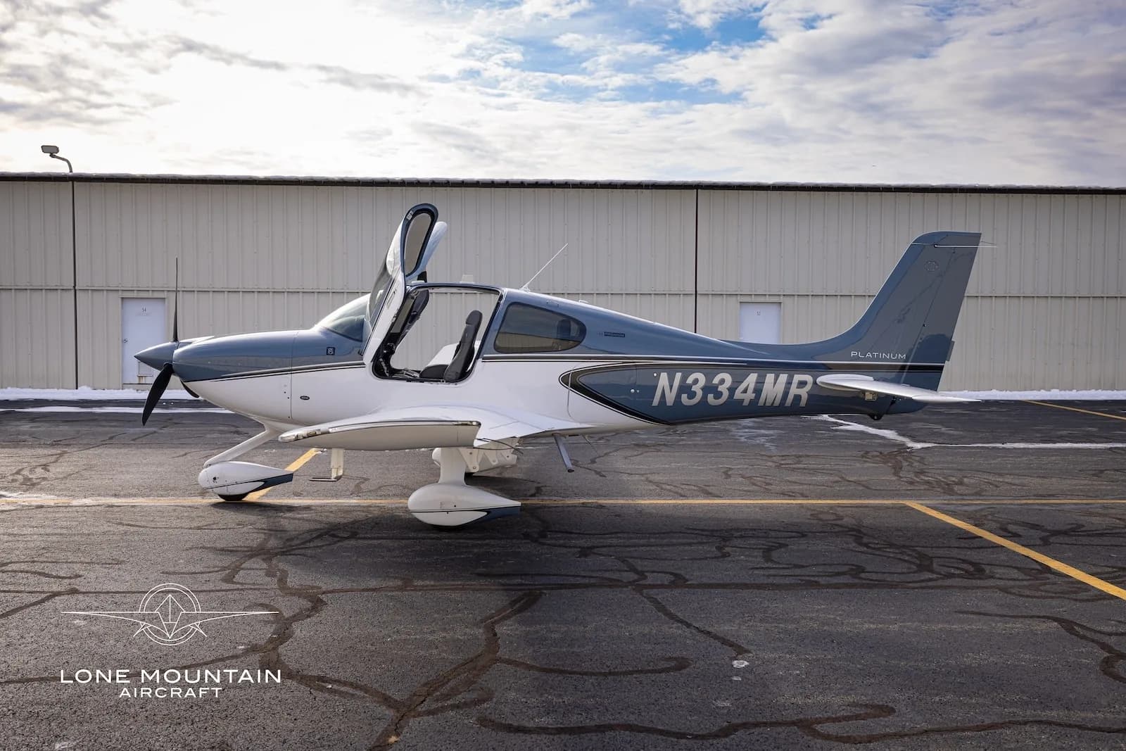 A side view of the Cirrus SR20 aircraft, N334MR, with its gull-wing doors open.